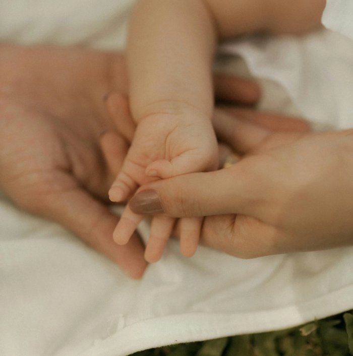 Mani di genitori che stringono il braccio di un neonato